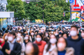 マスクをした通行人であふれかえる観光地の写真。